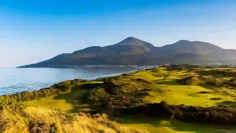 Royal County Down golf course stretches along the coast with the Mourne Mountains beyond, Newcastle, County Down.