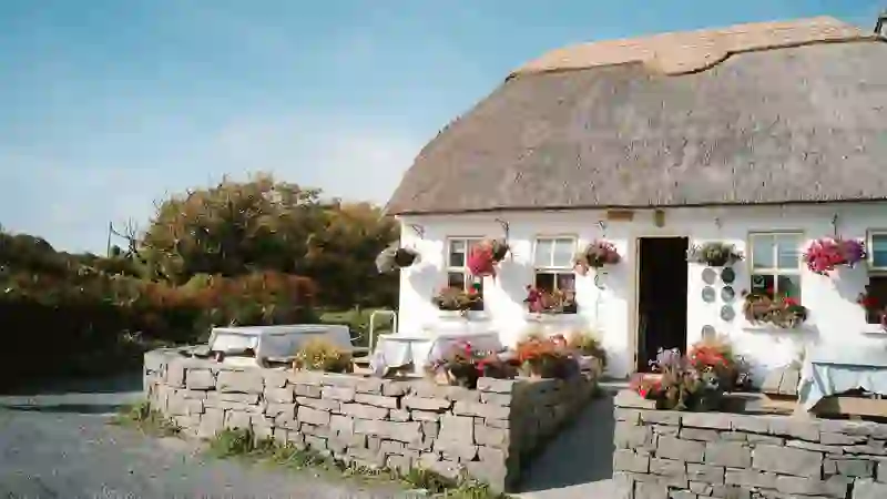 Thatched cottage with bright flowers and stone walls on the Aran Islands, County Galway.