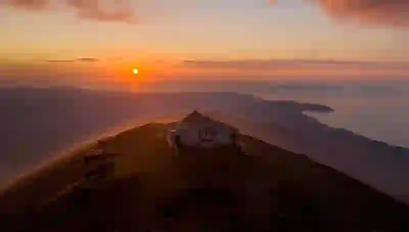 Hilltop chapel at sunset with sweeping views over coastline and islands, Croagh Patrick, County Mayo.
