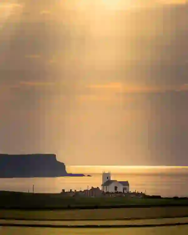 Ballintoy Church overlooking the Atlantic Ocean at sunset on the Causeway Coast, County Antrim.