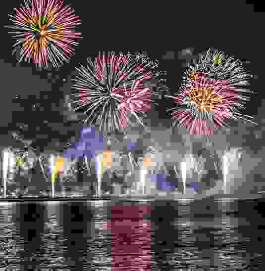 Vuurwerk boven Dublin Bay dat 's nachts kleurrijk licht weerkaatst op het kalme water.