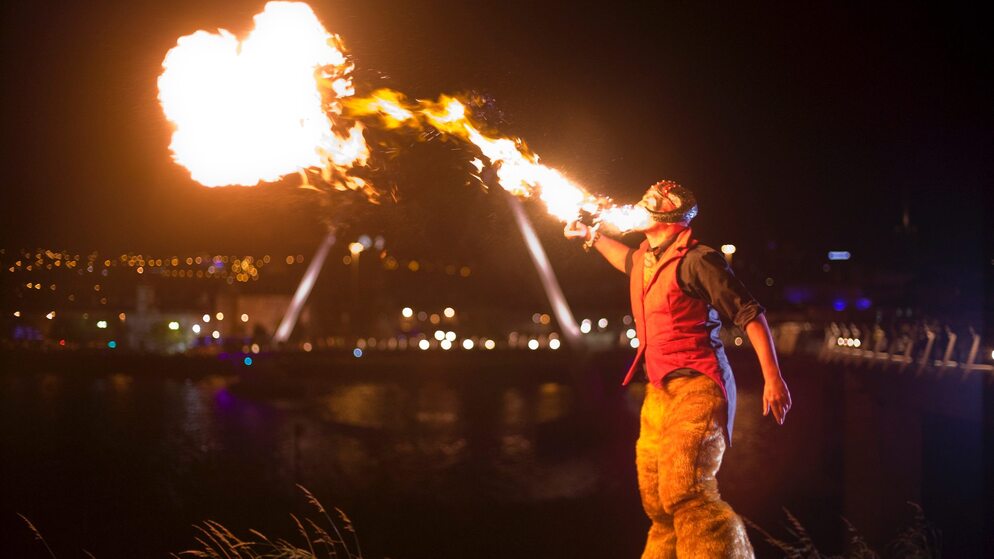 Artiste du feu soufflant des flammes dans le ciel nocturne lors du festival d'Halloween de Derry à Derry~Londonderry.