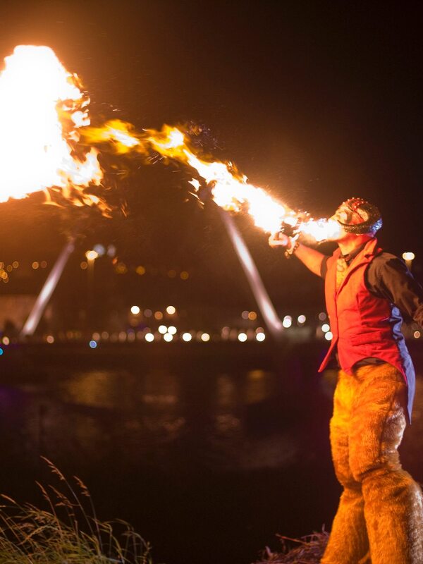 Fire performer breathing flames into the night sky at the Derry Halloween festival in Derry~Londonderry.