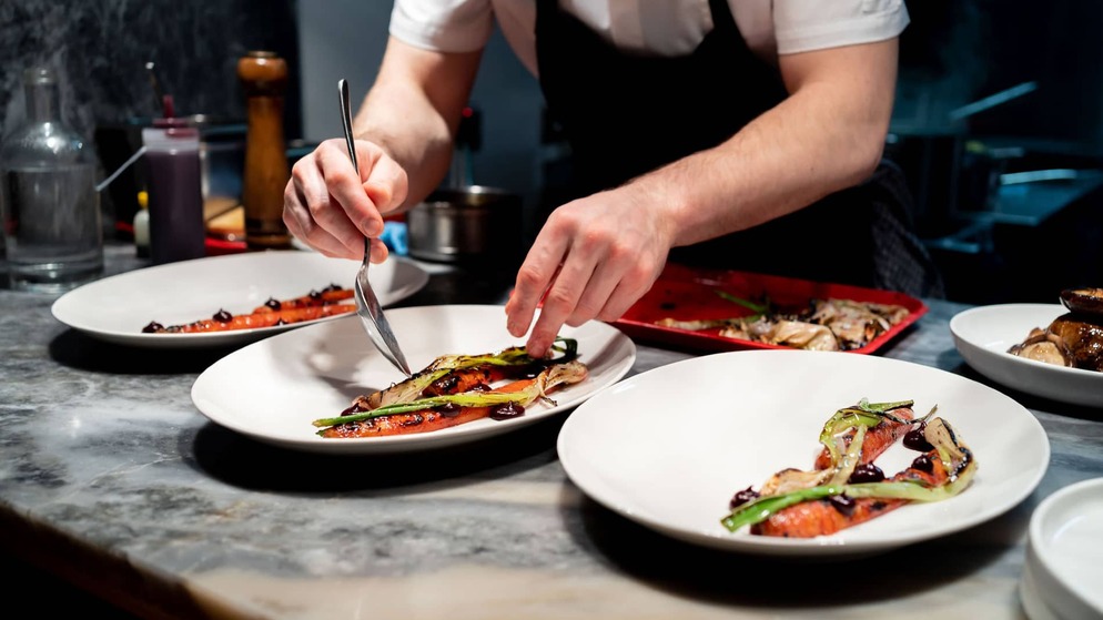 Chef plating grilled vegetables with sauce in a fine dining restaurant in Dublin.