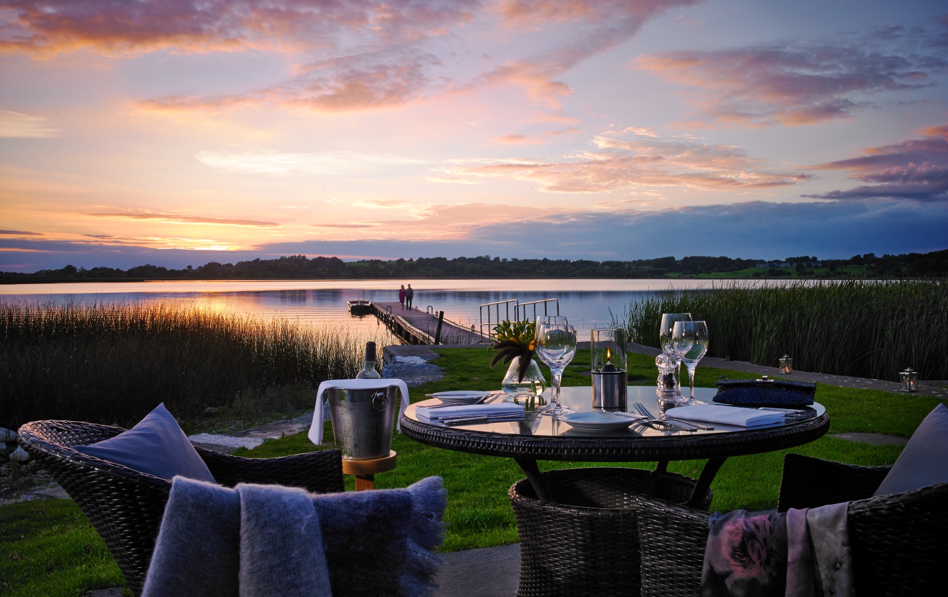 Romantic lakeside dining at sunset in Ireland’s Hidden Heartlands, with a jetty stretching into calm waters.