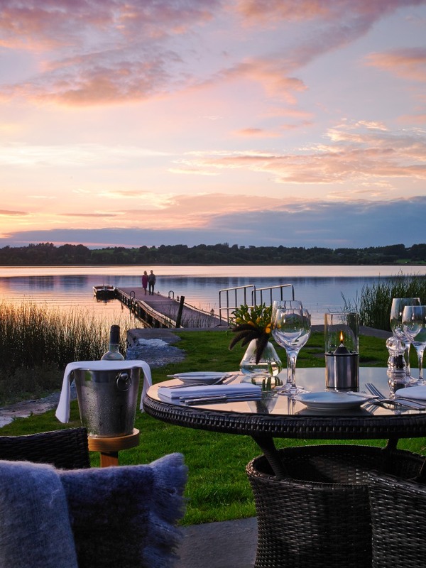 Romantic lakeside dining at sunset in Ireland’s Hidden Heartlands, with a jetty stretching into calm waters.