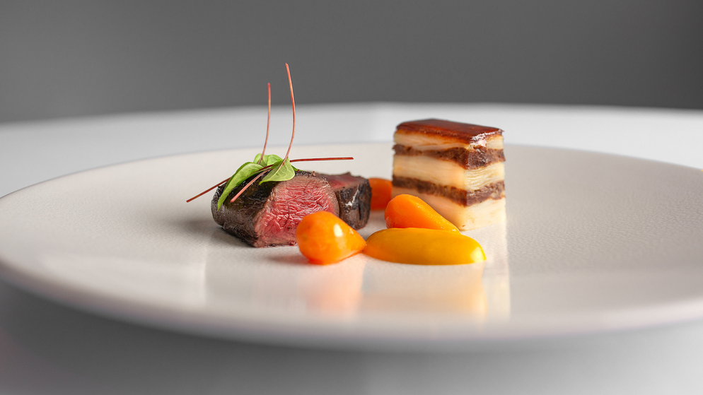Piatto raffinato a base di manzo con patate e verdure a strati in un ristorante stellato Michelin in Irlanda.