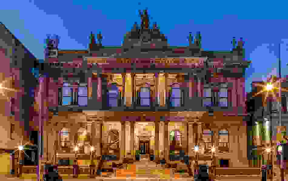 The Merchant Hotel Belfast illuminated at night with ornate historic façade.