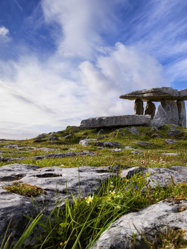 Kalkstein-Dolmen in Poulnabrone im Burren, Clare, unter einem dramatischen Himmel mit Wolkenstreifen.