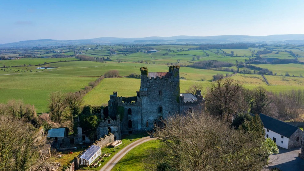 Die Ruinen von Leap Castle erheben sich unter einem klaren blauen Himmel über grünen Feldern und sanften Hügeln in der Grafschaft Offaly.
