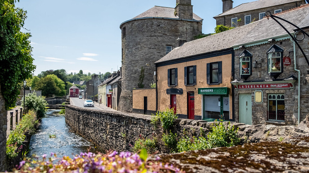 Historische ronde toren en winkels aan de rivier in Ierland op een zonnige zomerdag.