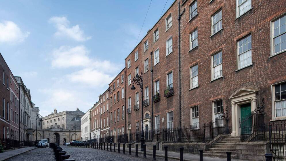 Georgian brick buildings on Henrietta Street, Dublin, under a blue sky with scattered clouds.