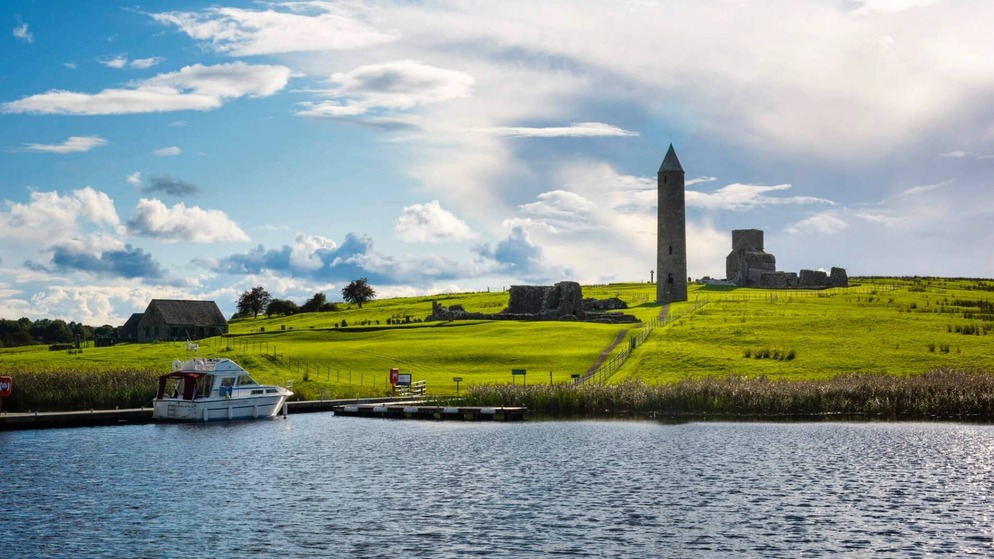 Barco atracado junto a la isla Devenish con una torre redonda y ruinas en el condado de Fermanagh.
