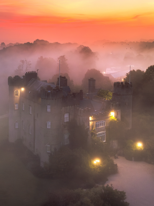 Malahide Castle illuminated at dawn through mist in Malahide, County Dublin.