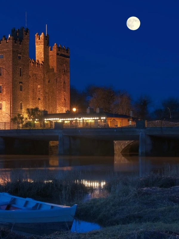 Bunratty Castle illuminated at night beside the River Shannon in County Clare, Ireland.