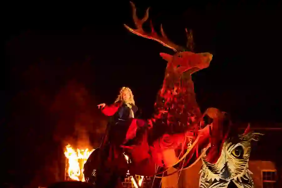 Performer in a cloak rides flaming antlered creature at night-time Samhain Festival in County Longford.