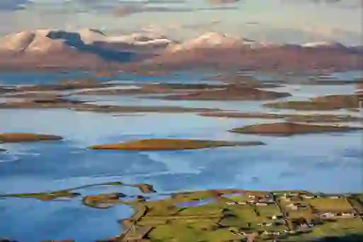 Panoramic view of Clew Bay in County Mayo, with its many islands, green fields and snow-capped mountains in the distance.