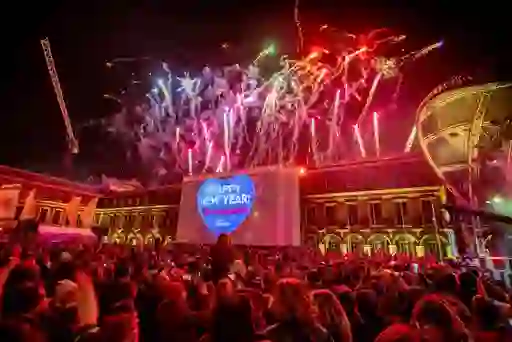 Colourful fireworks lighting up the night sky above Dublin Castle during New Year's Festival Dublin, with a large crowd watching and a Happy New Year projection on the building.