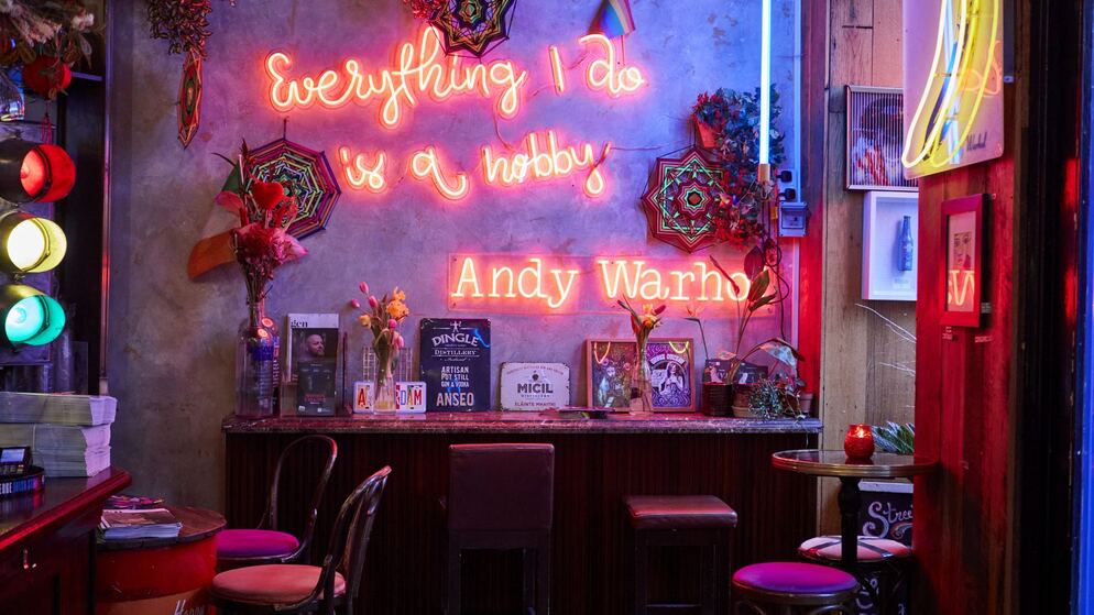 Een met neon verlichte bar in Dublin met een Andy Warhol-bord en een eclectisch regenboogdecor op Rainbow Mile.