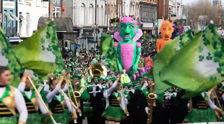 Marching band with green flags and giant fantasy figures at Dublin’s St Patrick’s Day parade.