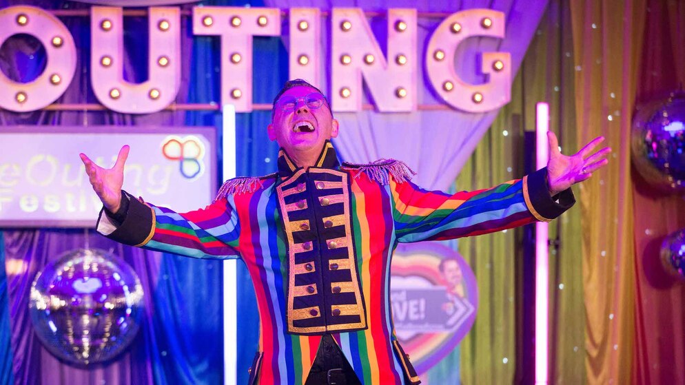Performer in a rainbow jacket on stage at The Outing LGBTQ+ festival in Ireland.