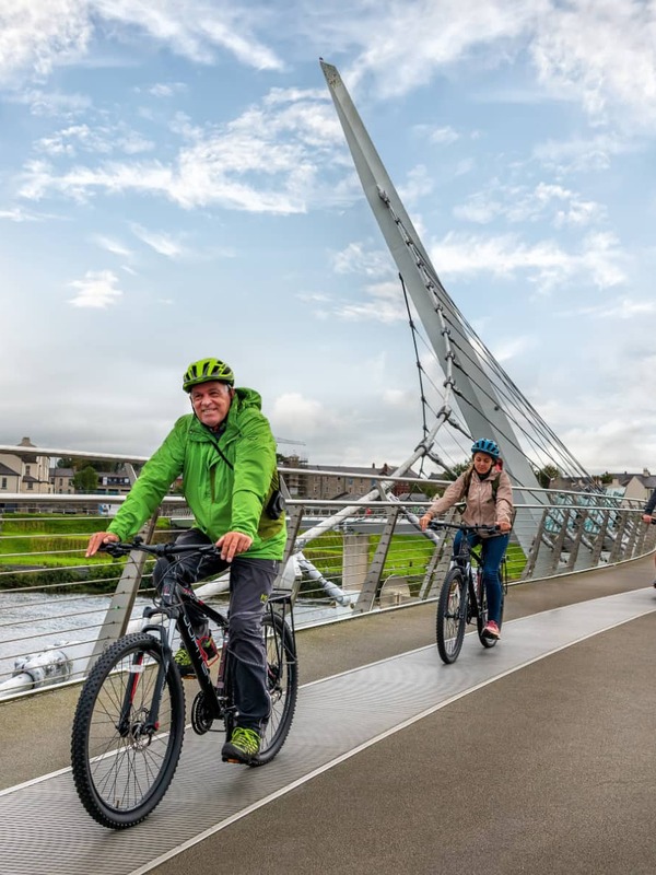 Cyclists crossing the Peace Bridge in Derry~Londonderry on a cloudy day.