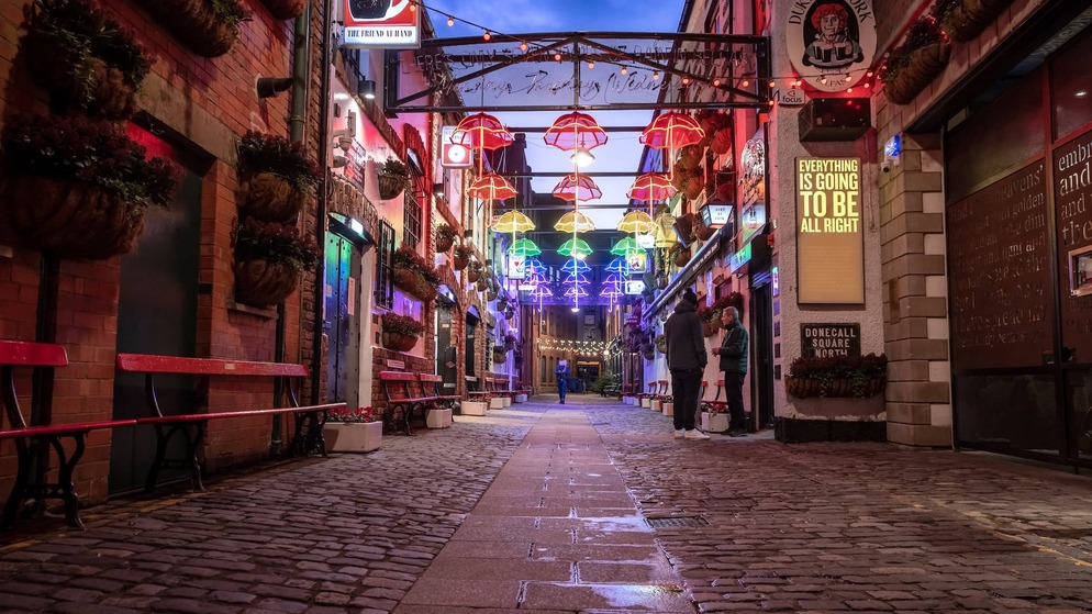 Colourful umbrella lights illuminate Commercial Court in Belfast’s Cathedral Quarter, a popular nightlife and pub district.