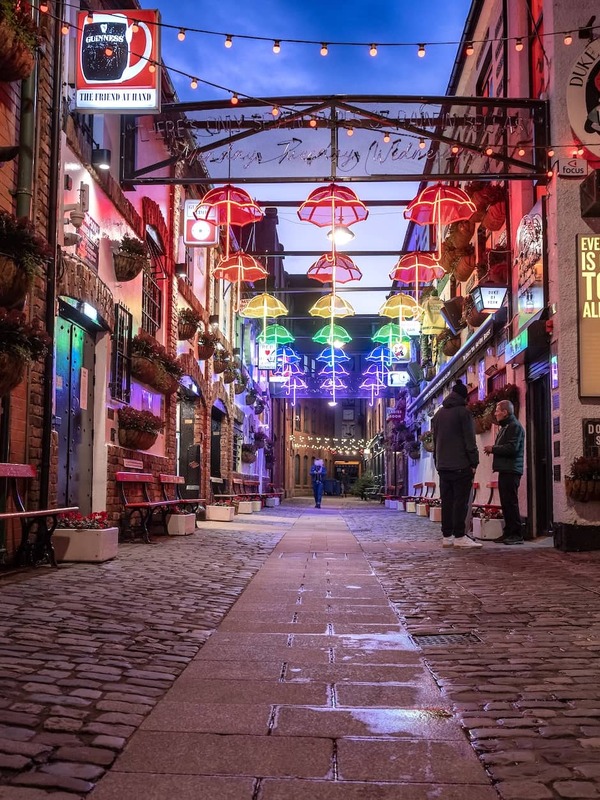 Colourful umbrella lights illuminate Commercial Court in Belfast’s Cathedral Quarter, a popular nightlife and pub district.