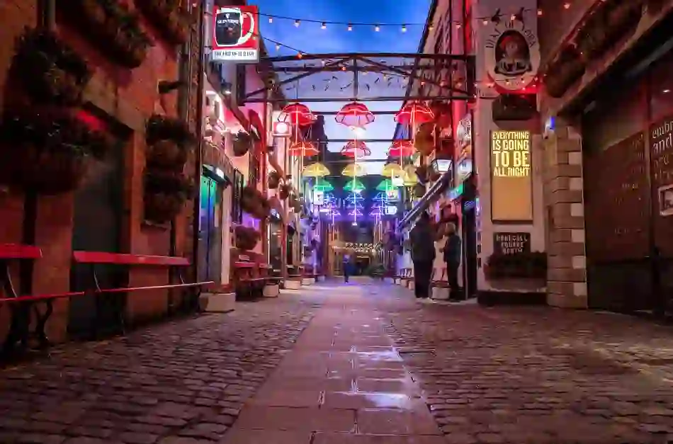 Colourful umbrella lights illuminate Commercial Court in Belfast’s Cathedral Quarter, a popular nightlife and pub district.