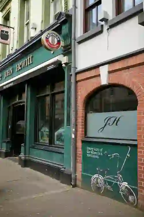 The John Hewitt pub in Belfast, with its traditional green frontage and bicycle artwork on the exterior wall.