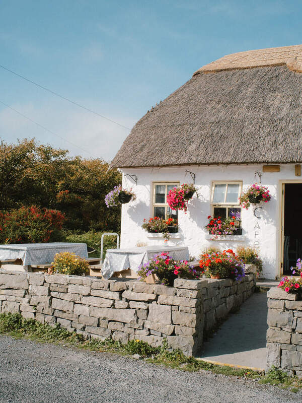 Traditional thatched café with flower-filled walls and outdoor tables on the Aran Islands, County Galway.