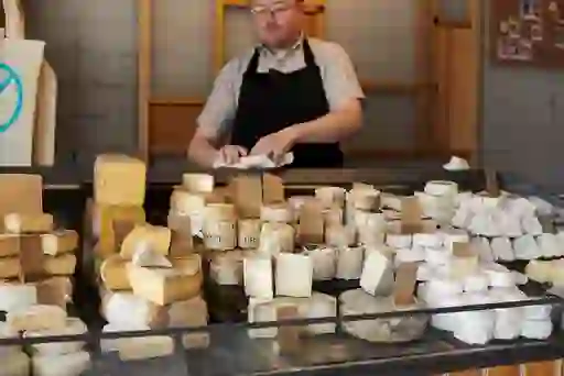 A cheesemonger with an array of different cheeses on display in the Cathedral Quarter, Belfast.
