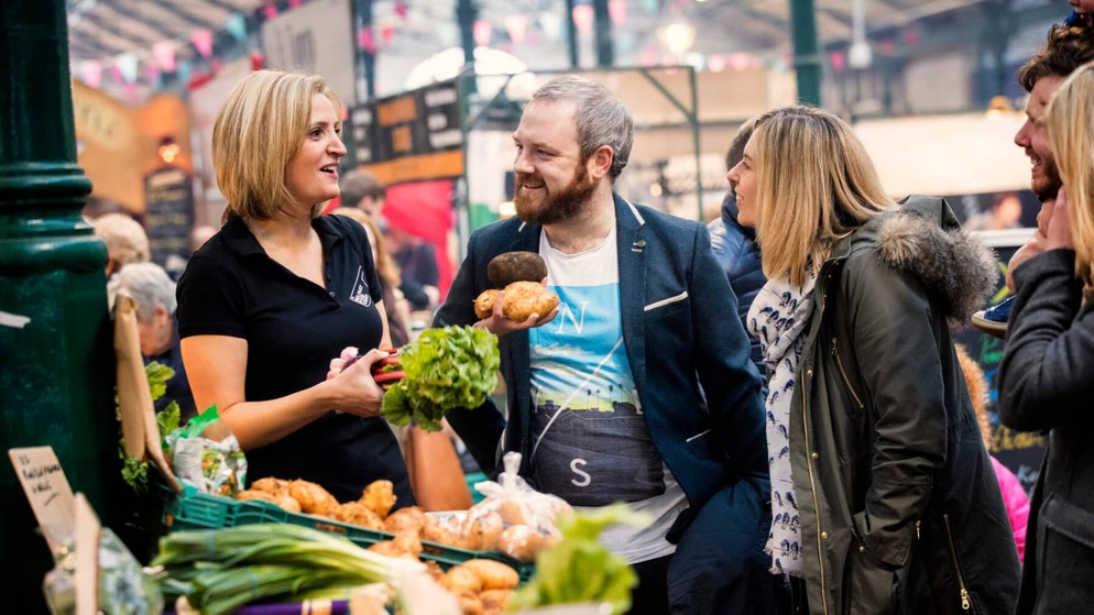 Taste and Tour guide chatting with visitors at St George’s Market in Belfast.