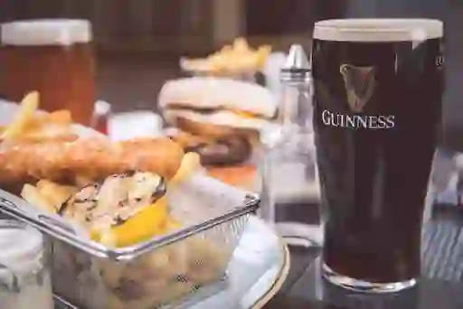 Fish and chips with grilled lemon beside a pint of Guinness and a burger at the Titanic Hotel Belfast.