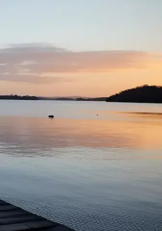 Ein Holzsteg erstreckt sich bei Sonnenuntergang in den Lower Lough Erne in der Grafschaft Fermanagh, Nordirland.