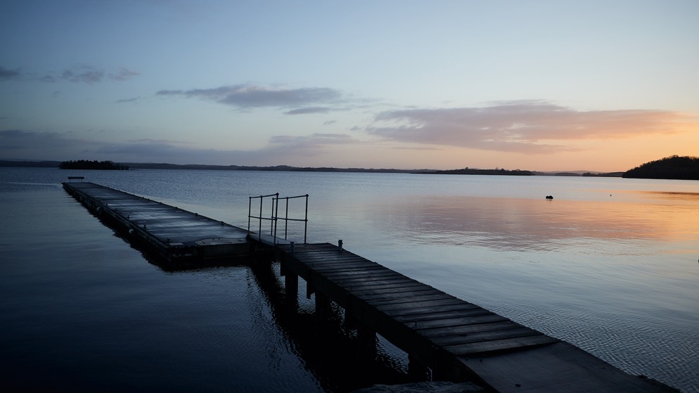 Ein Holzsteg erstreckt sich bei Sonnenuntergang in den Lower Lough Erne in der Grafschaft Fermanagh, Nordirland.