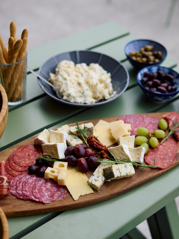 Charcuterie board with cheeses, cured meats and grapes beside salad and snacks at Wild Atlantic Glamping, West Cork.