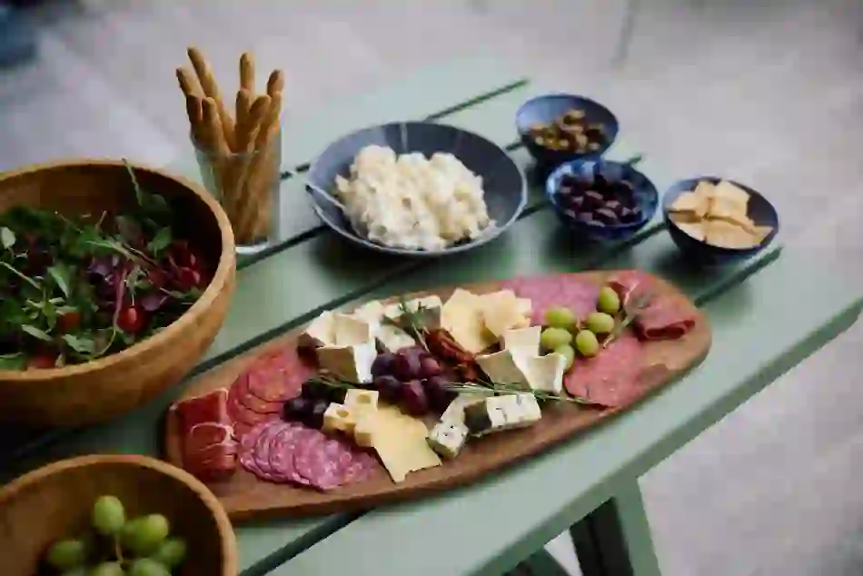 Charcuterie board with cheeses, cured meats and grapes beside salad and snacks at Wild Atlantic Glamping, West Cork.