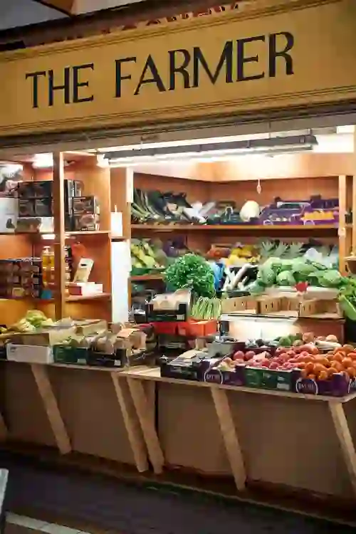 A colourful fruit and vegetable stall beneath a sign reading “The Farmer” at Cork’s English Market.