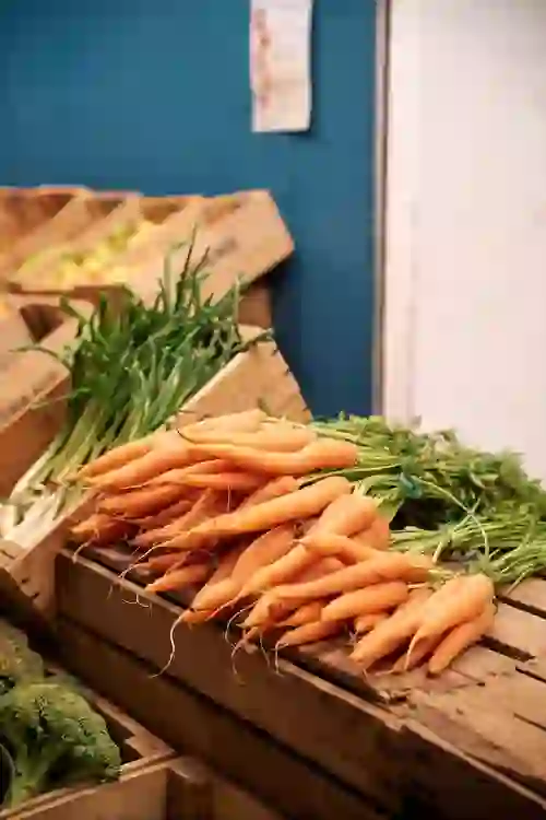 Bunches of fresh carrots and other vegetables displayed in wooden crates at a market stall in Cork's English Market.