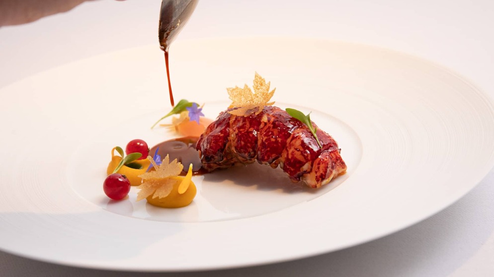 Sauce being poured over an elegant lobster dish with colourful garnishes at Chapter One, Dublin.