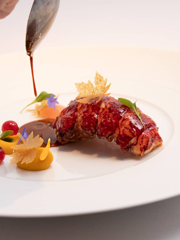 Sauce being poured over an elegant lobster dish with colourful garnishes at Chapter One, Dublin.