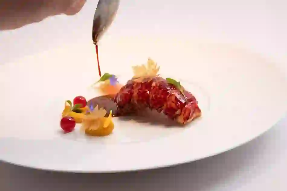 Sauce being poured over an elegant lobster dish with colourful garnishes at Chapter One, Dublin.