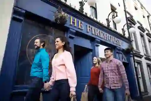 Deux couples se promènent main dans la main devant la façade bleue du bar grill The Firehouse à Enniskillen, dans le comté de Fermanagh.