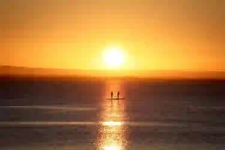 Paddleboarders silhouetted against the sunset on Galway Bay in Salthill, Galway.