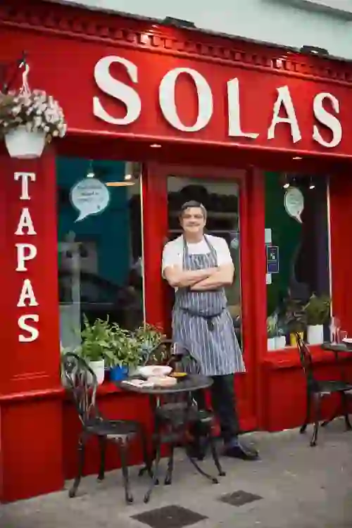 Ein Koch vor dem leuchtend roten Solas Tapas-Restaurant in Dingle, Grafschaft Kerry.