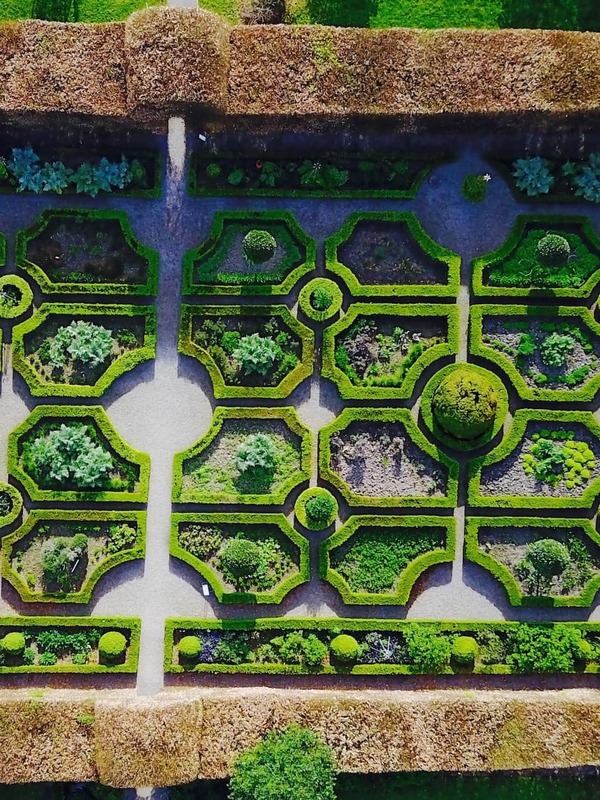 Aerial view of a formal walled garden with geometric hedges and pathways.