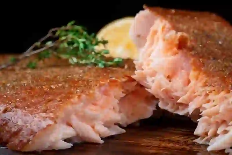 Flaky hot-smoked salmon fillet with crisp skin, served with lemon and fresh thyme.