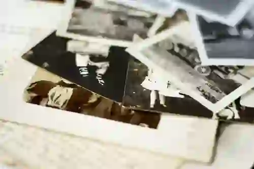 Scattered vintage black-and-white family photographs laid out on top of handwritten documents.