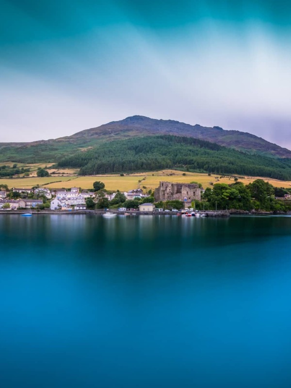 Vista panoramica del villaggio di Carlingford e del Castello di Re Giovanni con le montagne Cooley che si innalzano sopra il Lough.